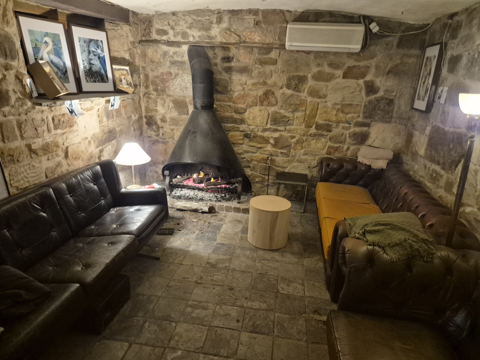 Leather couches around an open fire in the stone cellar lounge