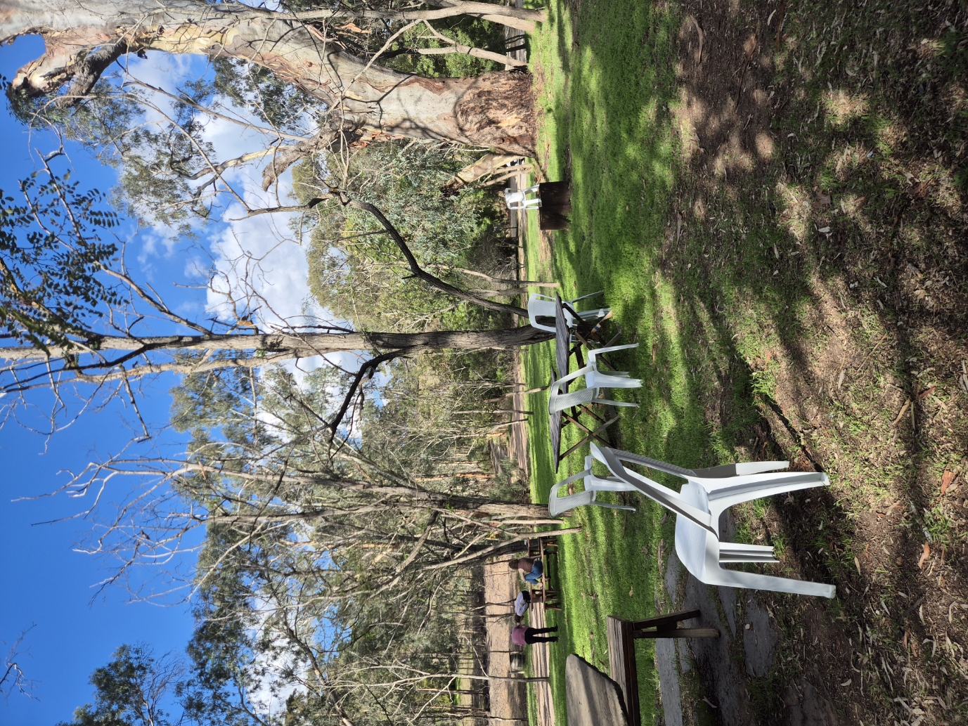 Tables and chairs on the gum-shaded lawn at Jeanneret Rd