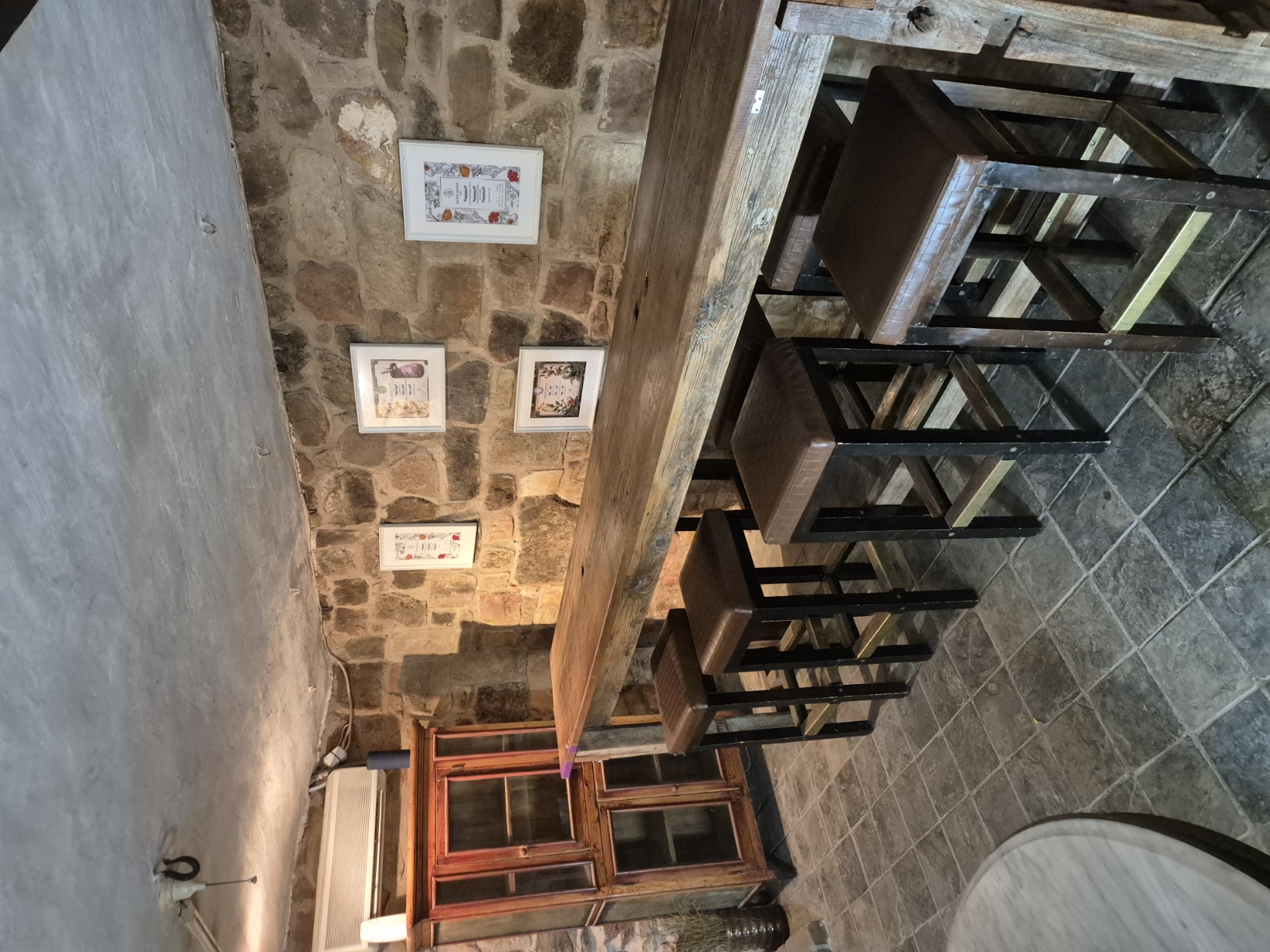 Long salvaged-timber bar and stools against the stone cellar wall